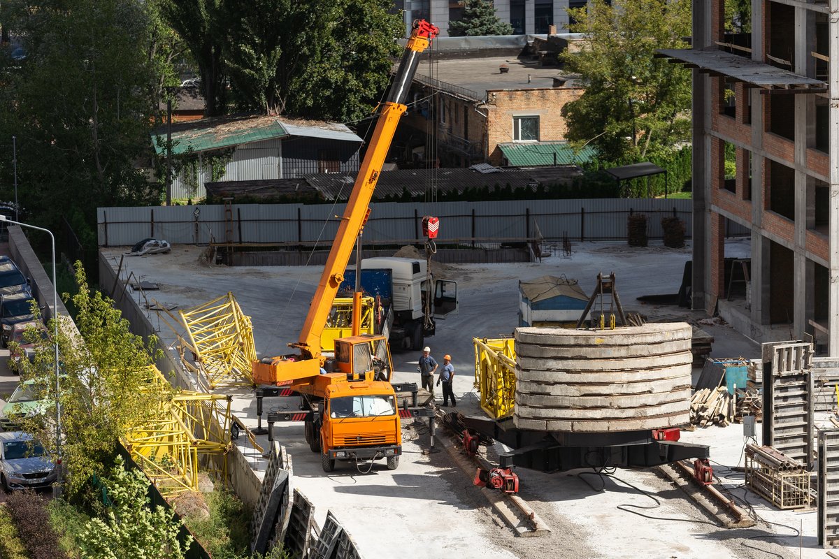 Camion-grue positionné avec stabilisateurs déployés lors d'une opération de levage sur chantier