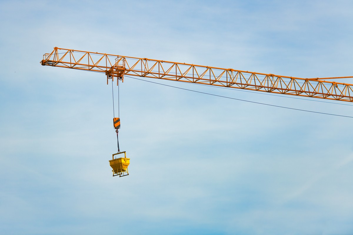 Opération de levage avec élingage de la charge et zone de sécurité balisée sur chantier