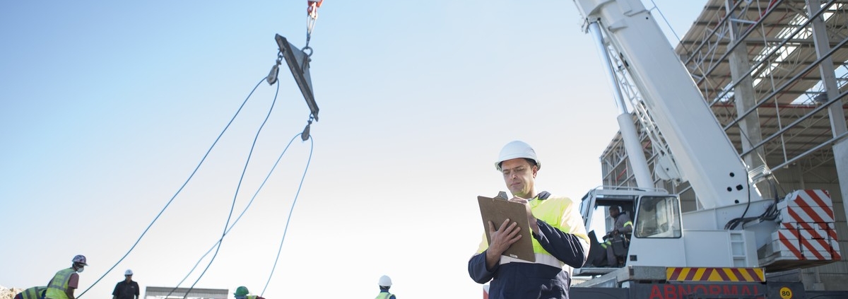 Opérateur préparant un plan de levage avant une opération avec camion-grue sur chantier